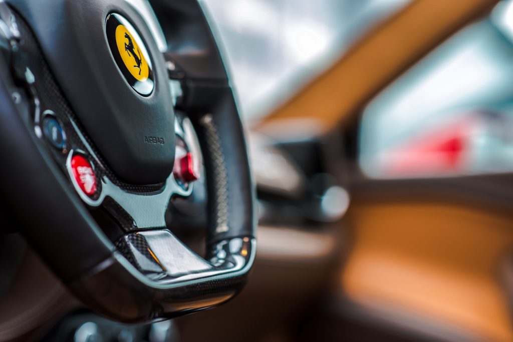 ferrari steering wheel, the ferrari logo in yellow, engine start button